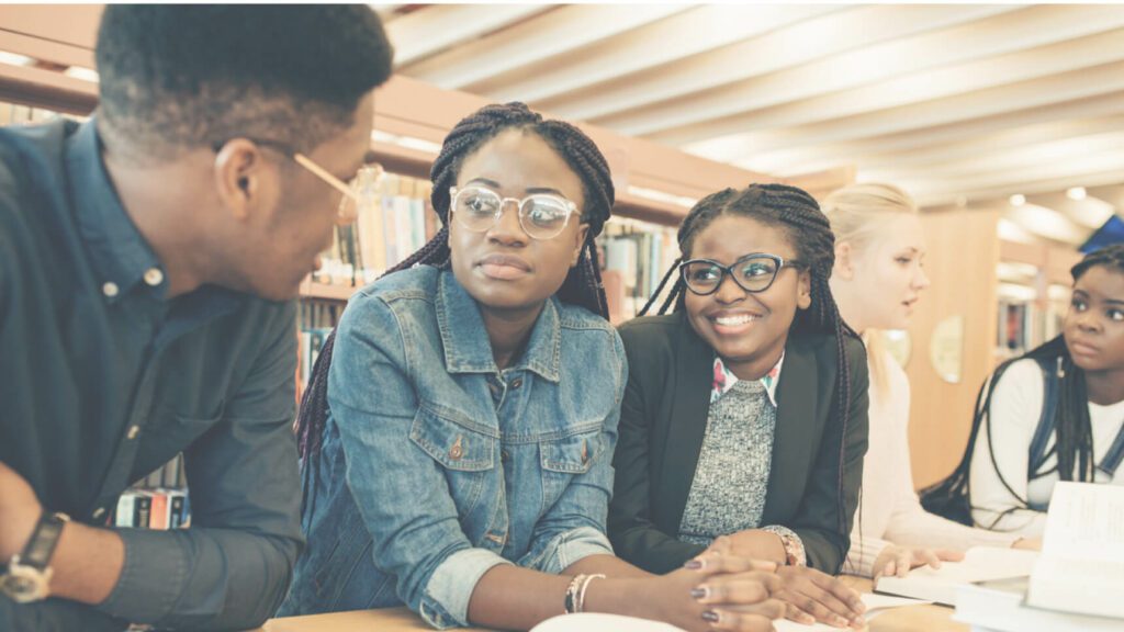 Three people sitting at a table in front of books.