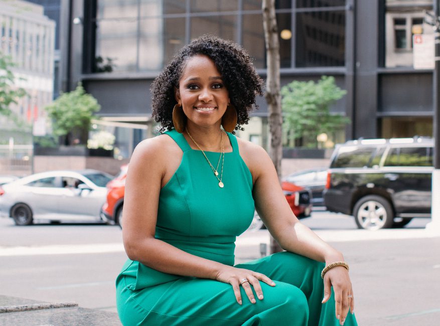 A woman in green dress sitting on the side of road.