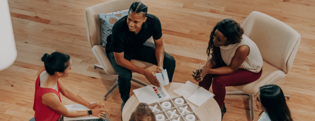 A man playing tic tac toe with two women.