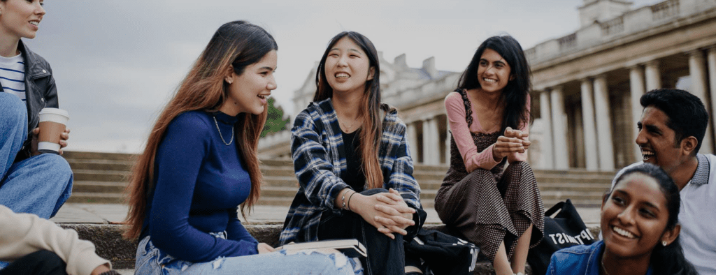 Three women sitting on a bench talking to each other.