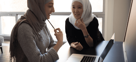 Two women sitting at a table with a laptop