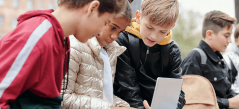 Three boys looking at a laptop computer.
