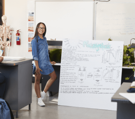 A woman standing next to a whiteboard in an office.