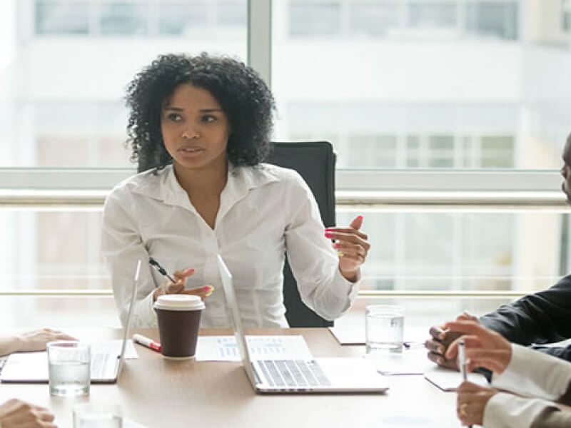 A woman sitting at a table with two other people.