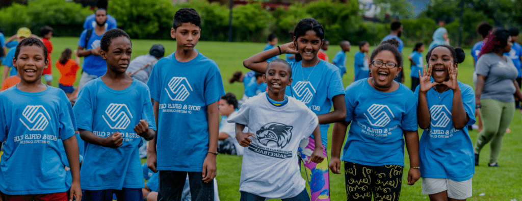 A group of young people in blue shirts standing on top of a green field.