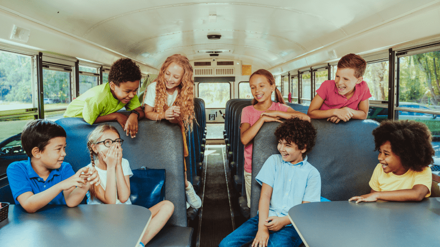 A group of children sitting on the seats in a bus.