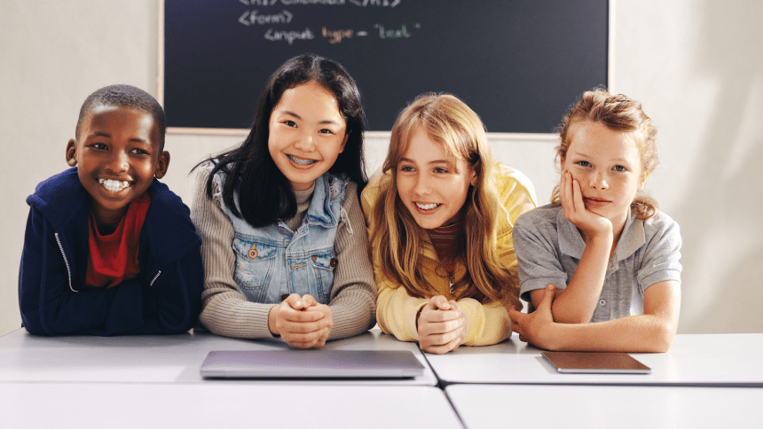 Four girls are sitting at a table with their hands on their hips.