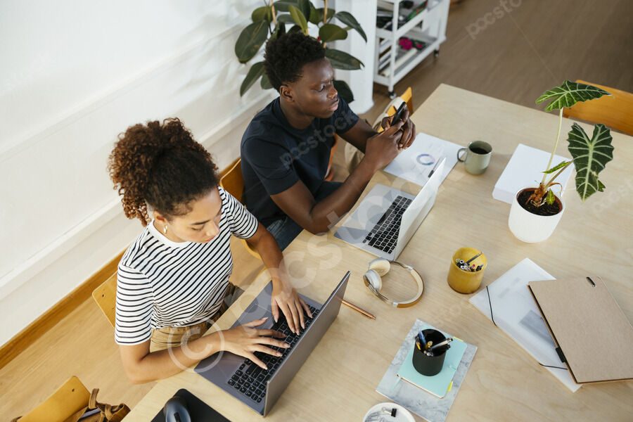 Two people working on laptops at table.