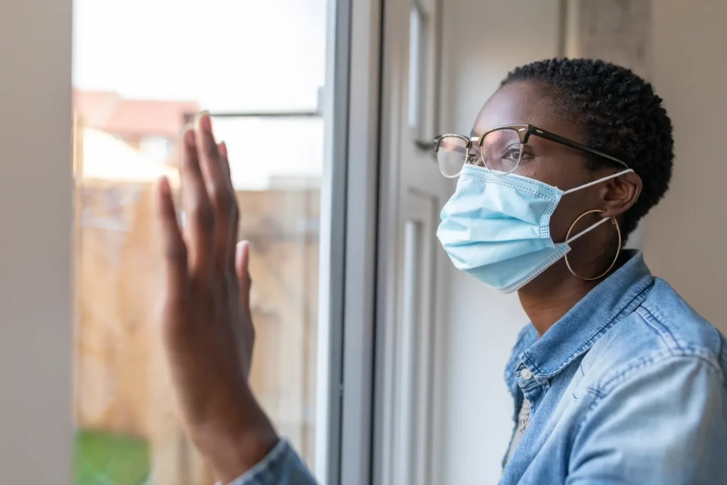 Person wearing mask looking out window.