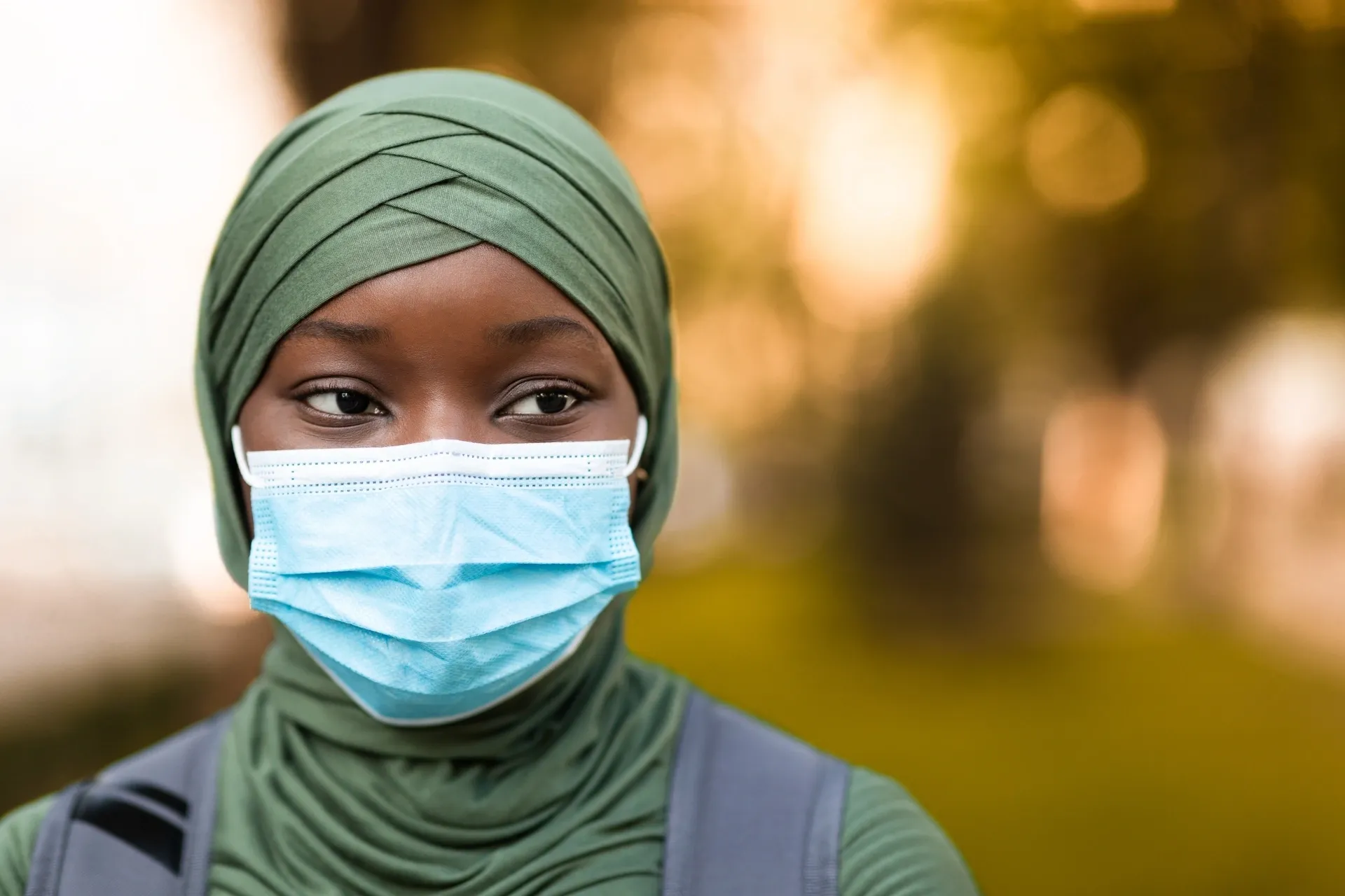 Person wearing green hijab and blue mask.